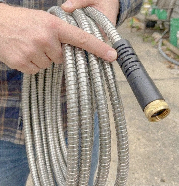 Close-up of the Garden Maestros hose brass fitting and stainless steel coil texture